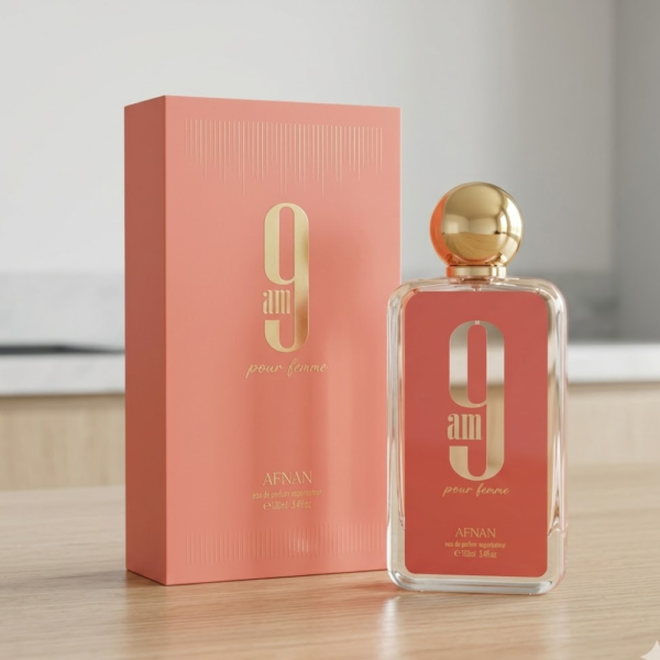 Frasco de perfume 9AM Coral de Afnan color coral con tapa redonda dorada sobre fondo luminoso.