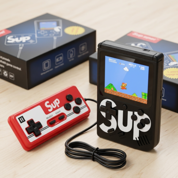 Consola portátil Sup negra con pantalla encendida mostrando juego de Mario y control rojo adicional sobre mesa de madera.